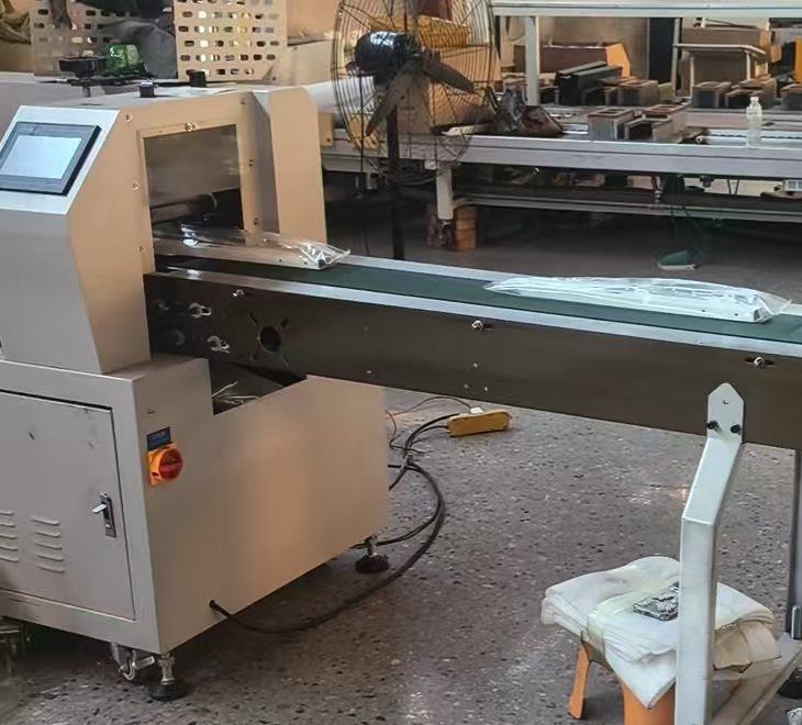 A wrapped component on a conveyor beside a workshop packaging machine